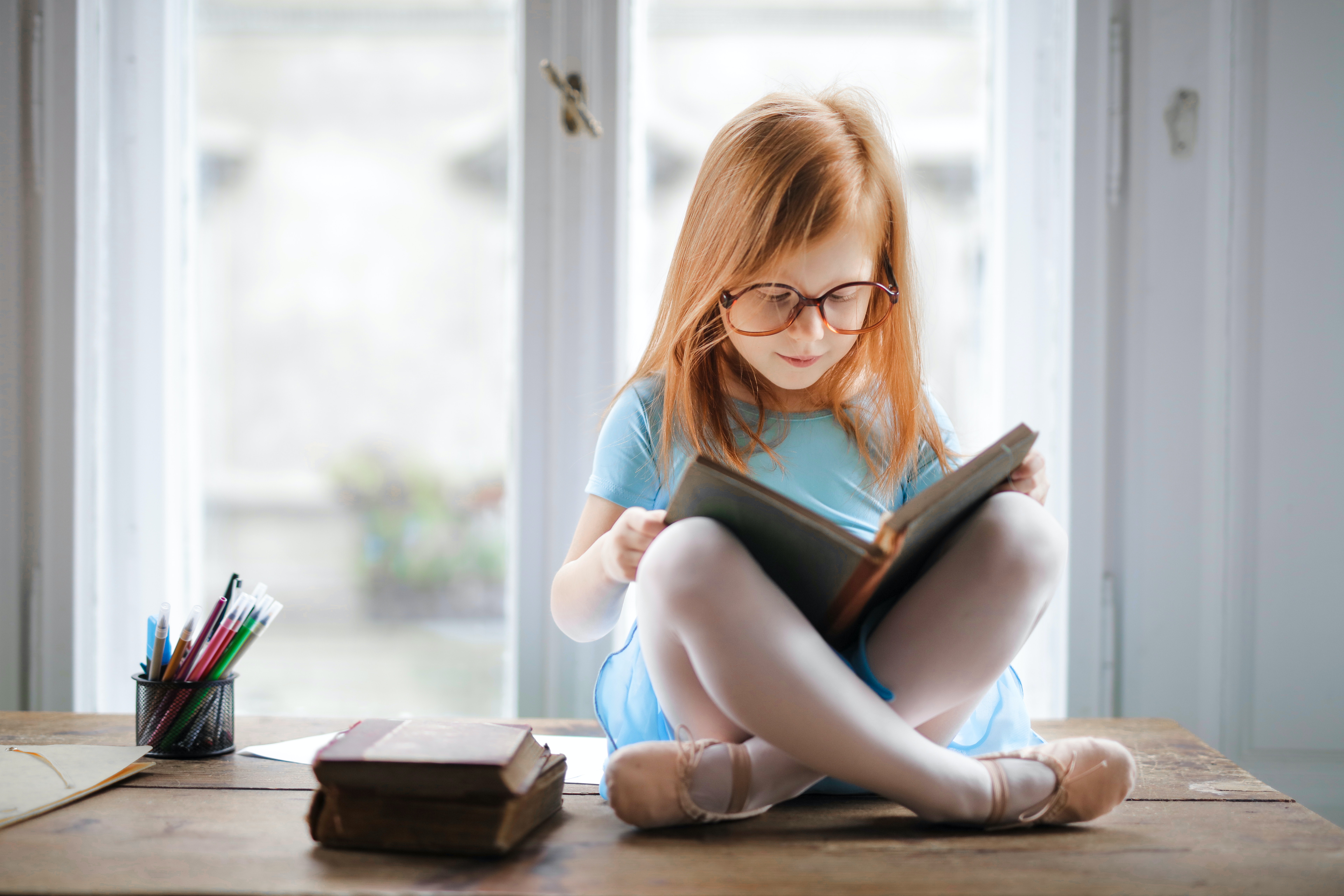 menina ruiva lendo um livro de pernas cruzadas