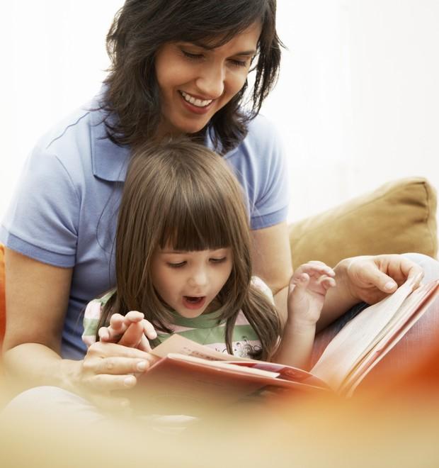 Mãe e filha com um livro em mãos (Foto: Thinkstock)