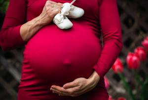 Grávida segurando barriga e sapatinho de bebê