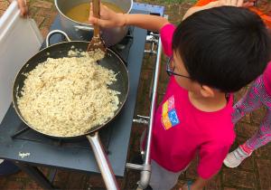 Criança mexendo panela de arroz