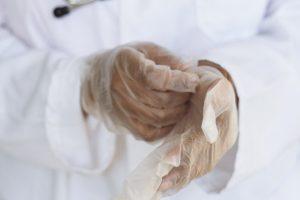 Mãos de médico com luvas de plástico