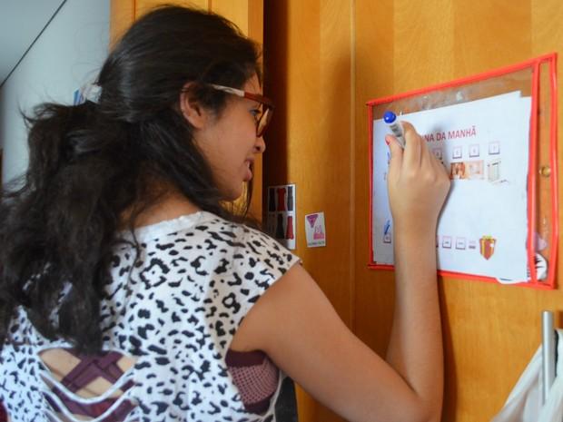Júlia sinaliza no quadro as tarefas que realizou após acordar (Foto: Gabriela Castilho/G1)