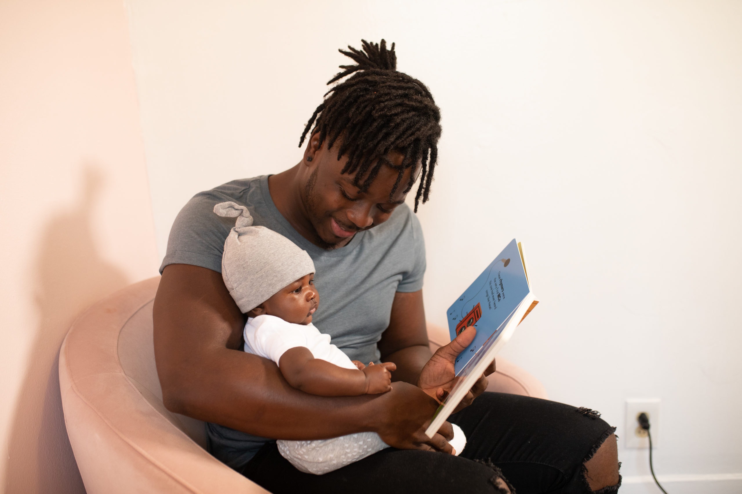 Pai com um bebê no colo segurando um livro