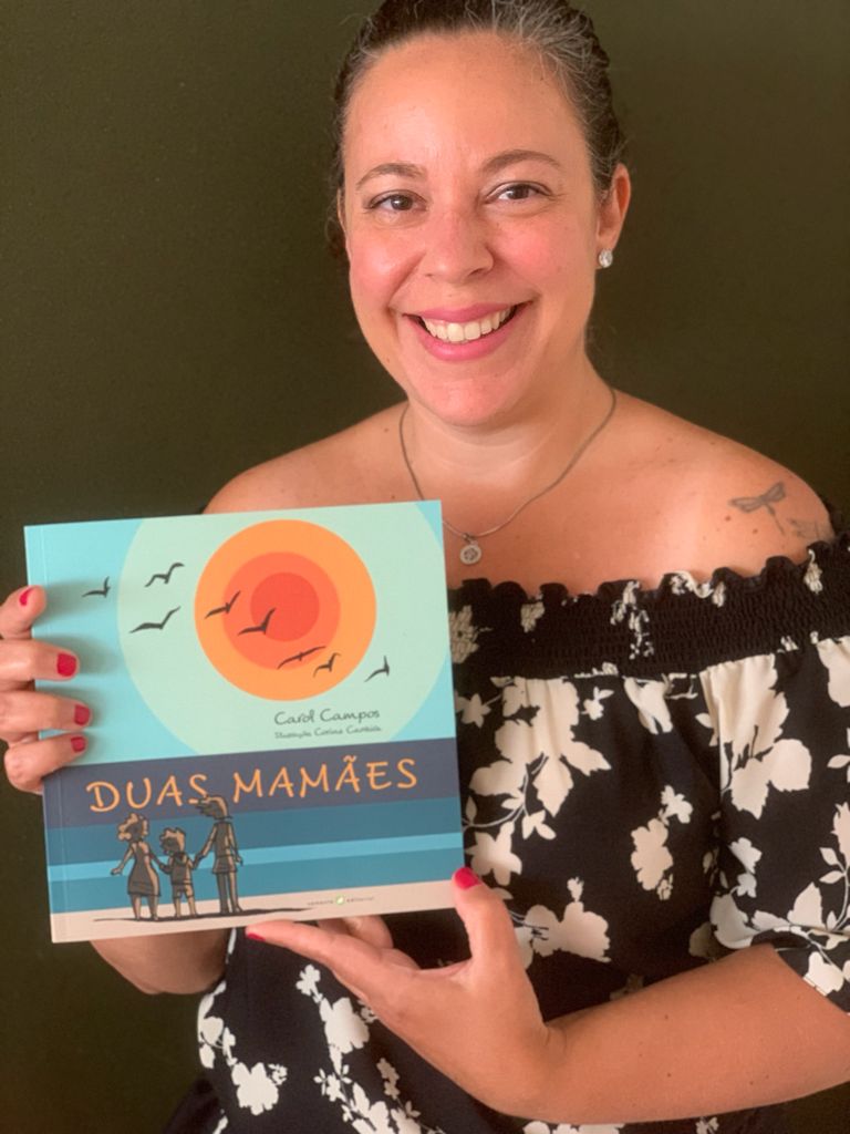 Carol Campos segurando o livro "Duas Mamães"