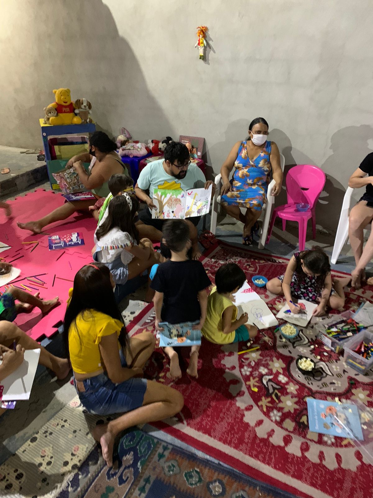 Crianças e pais sentadas em um tapete com livros